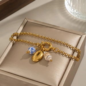Detailed view of ocean theme bracelet with ceramic bead, shell, and conch charms