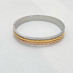 Macro shot of tricolor mixed metal star bangle featuring gold and silver weave detail