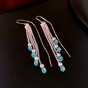 Elegant gold drop earrings with lake blue stones and long zircon tassels on black leather