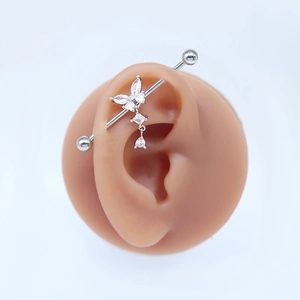 Detail of silver industrial piercing with butterfly zircon design on a silicone ear model
