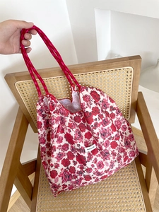 Detailed shot of floral canvas tote bag with red rope handles and have a nice day label