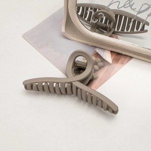 Detail of matte cream shark hair claw clip with non-slip teeth on a modern mirror background