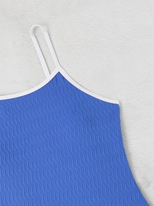 Detail of blue backless swimsuit featuring wave texture fabric and white piping trim