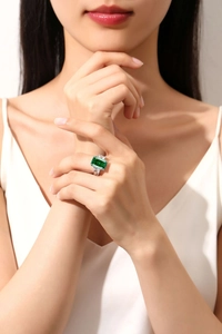 Macro shot of an elegant emerald-cut green gemstone ring worn on a finger