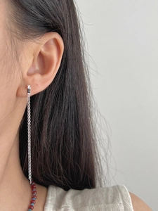 Detail of long tassel chain earring with black zircon on model for length reference