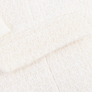 Macro view of woven tweed fabric texture and pocket flap detail on the white blazer