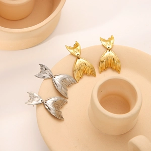 Retro stainless steel fishtail earrings in gold and silver finish on ceramic tray