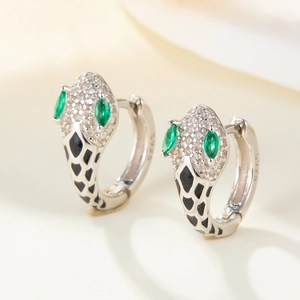 Macro shot of S925 silver snake earrings with green gem eyes and black enamel scales