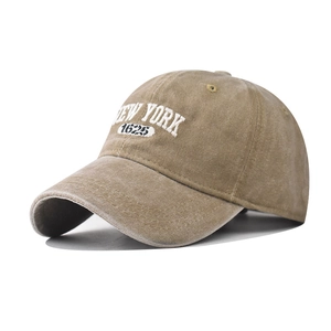 Detailed macro view of white 3D NEW YORK embroidery on a khaki washed cotton baseball cap