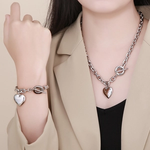 Model wearing silver heart pendant necklace and bracelet set with T-bar toggle clasp