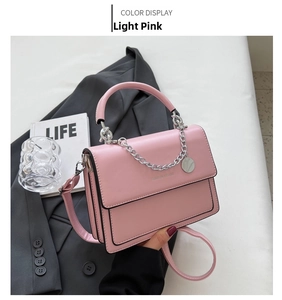 Detail view of light pink square crossbody bag with silver chain and fashion logo