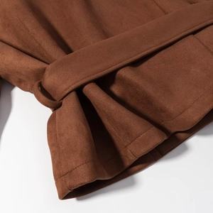 Detailed close-up of brown faux suede jacket featuring double-breasted belt and fine stitching