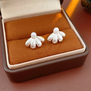 Macro detail of vintage floral pearl earrings displayed in a luxury brown leather jewelry box