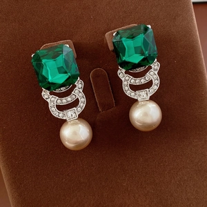 Vintage style drop earrings with green gemstone and pearl dangles on jewelry display