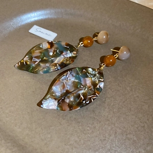 Detail of vintage leaf pendant earrings with marble texture resin and golden accents