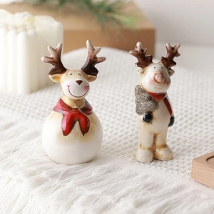 Ceramic Christmas reindeer ornaments with red scarves and mini tree on white knit rug