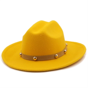 Detailed texture of yellow wool fedora hat featuring light brown band with gold metal studs