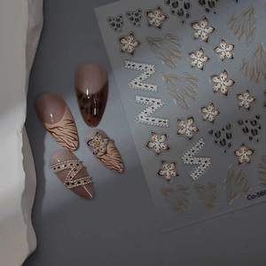 Detail of pink leopard print nail stickers with pearl N letter and floral French patterns