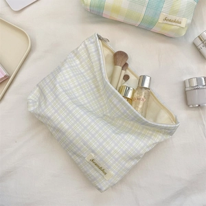 Detail of checkered canvas cosmetic bag with Sezakka label and top zipper closure