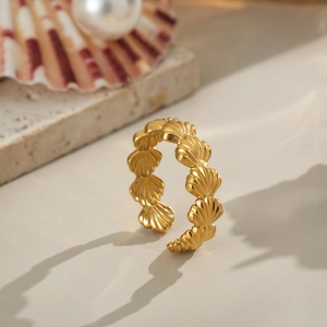 Minimalistischer goldener Muschelring auf Marmor mit Perlen und Muscheln dekoriert