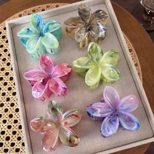 Set of six colorful marble-patterned acetate plumeria flower hair claws in a tray