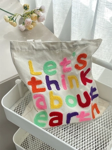 Detail of colorful towel embroidery with Let's think about earth text on canvas tote bag