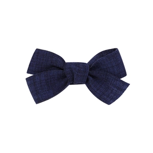 Detail view of a handcrafted dark blue fabric bow hair clip with textured fabric material