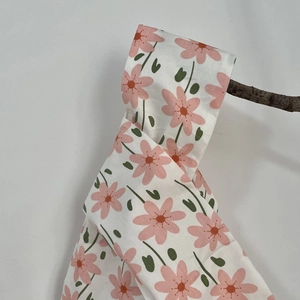 Floral cotton wrist bag with pink flowers hanging on a branch against a white wall