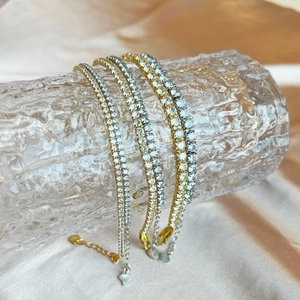 Detailed close-up of gold and silver tennis bracelets with zircon hearts on silk fabric