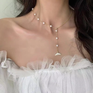 Detailed close-up of elegant gold Y-shaped necklace with pearls and diamond fishtail charm