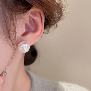 Close-up of minimalist white pearl earring on model for a French vintage luxury style