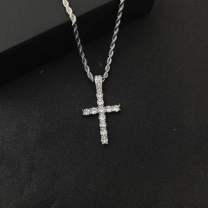 Macro shot of a silver hip hop cross pendant with clear crystals on a black twist chain
