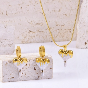 Close-up of heart-shaped necklace and earrings with gold finish and white lava texture