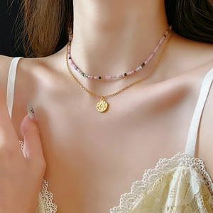 Détail d'un collier de perles à double rang avec pendentif étoile dorée sur modèle