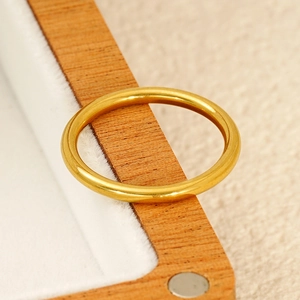 Detail of polished gold titanium minimalist ring resting on a wood frame with soft lining