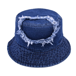 Detail view of deep blue denim bucket hat showing frayed circular patch and reinforced stitching