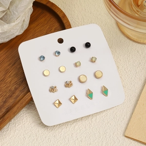 Détail de 9 paires de boucles d'oreilles dorées avec strass sur carte de bijoux
