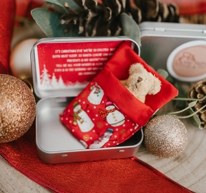 Christmas gift set featuring a mini beige teddy bear in a red snowman bag inside a silver box