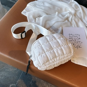 Detailed view of a white quilted crossbody chest bag with adjustable strap on leather
