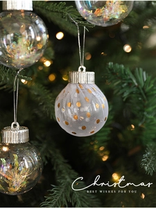 Detail of a white mesh Christmas ball with gold dots hanging on a festive tree branch