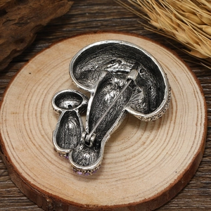 Retro paddenstoel broche met paarse zirkonen en antieke zilveren afwerking op hout