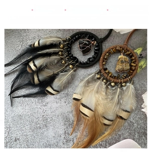 Detail of bohemian car pendant featuring natural feathers and woven stone charms