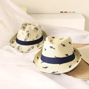 Close-up of kids straw sun hat featuring cartoon shark and palm tree prints with navy band