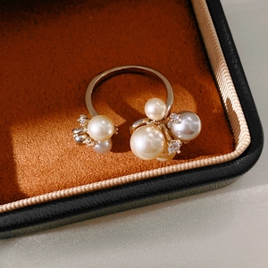 Detailed view of zircon and shell pearl cluster ring on warm velvet gift box