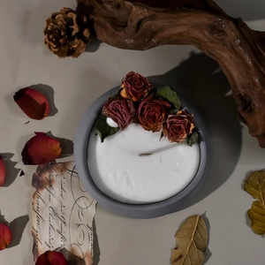 Vista superior de vela de rosa artesanal en tarro gris con mecha de madera y papel