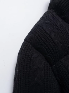 Close-up of black knit fabric texture and shoulder detail on a loose cardigan