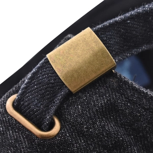 Macro view of adjustable bronze metal buckle and washed denim texture on baseball cap