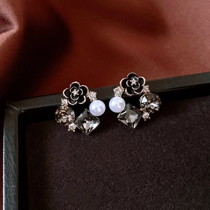 Detail showing vintage black camellia earrings with white pearl and grey crystals