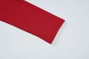 Detailed macro view of the red knitted sleeve texture and fine stitching on the mesh dress
