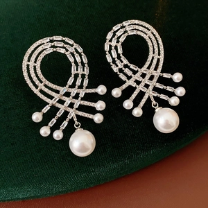 Vue macro des boucles d'oreilles en argent avec zircon et perles sur velours vert